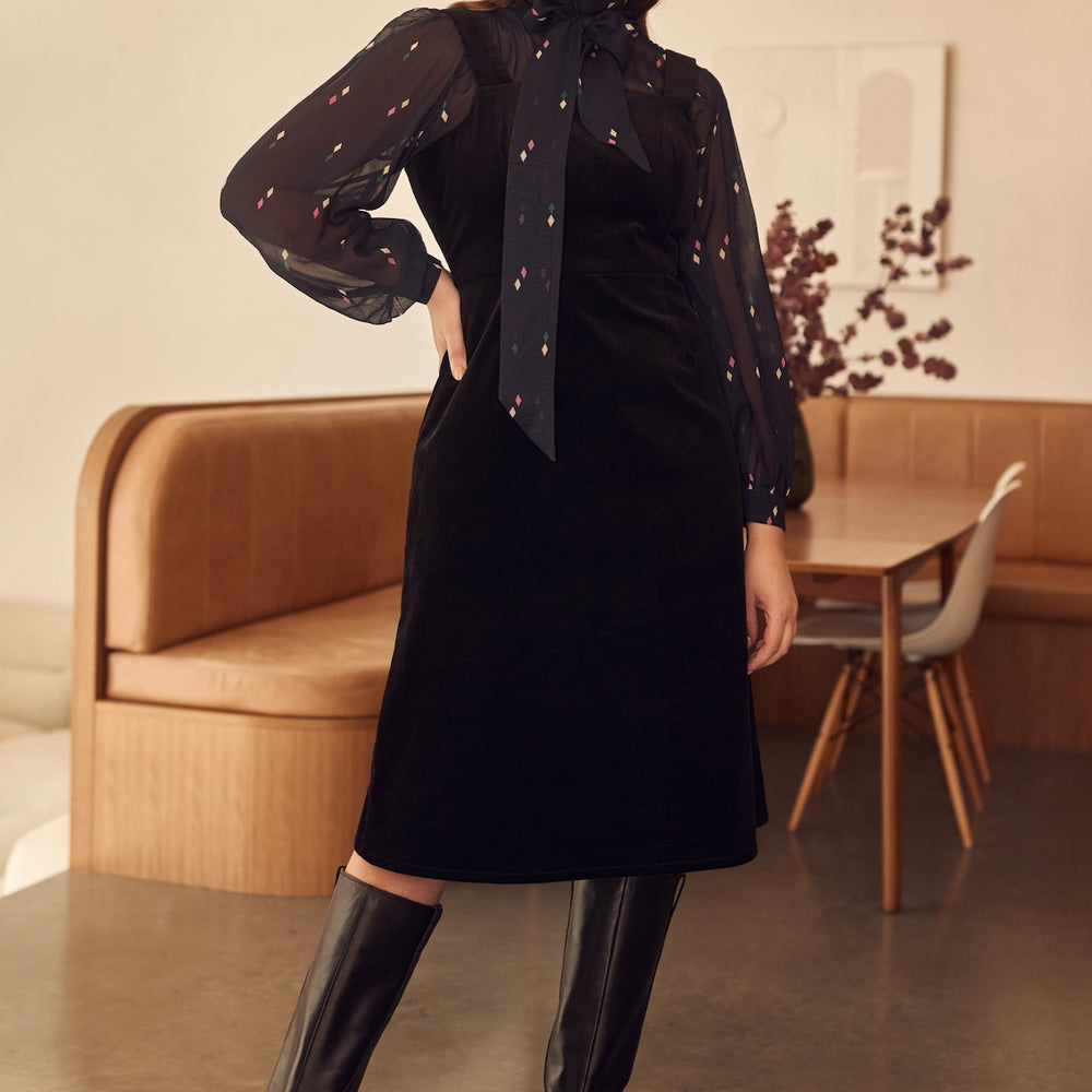 Black corduroy pinafore style apron dress with adjustable straps