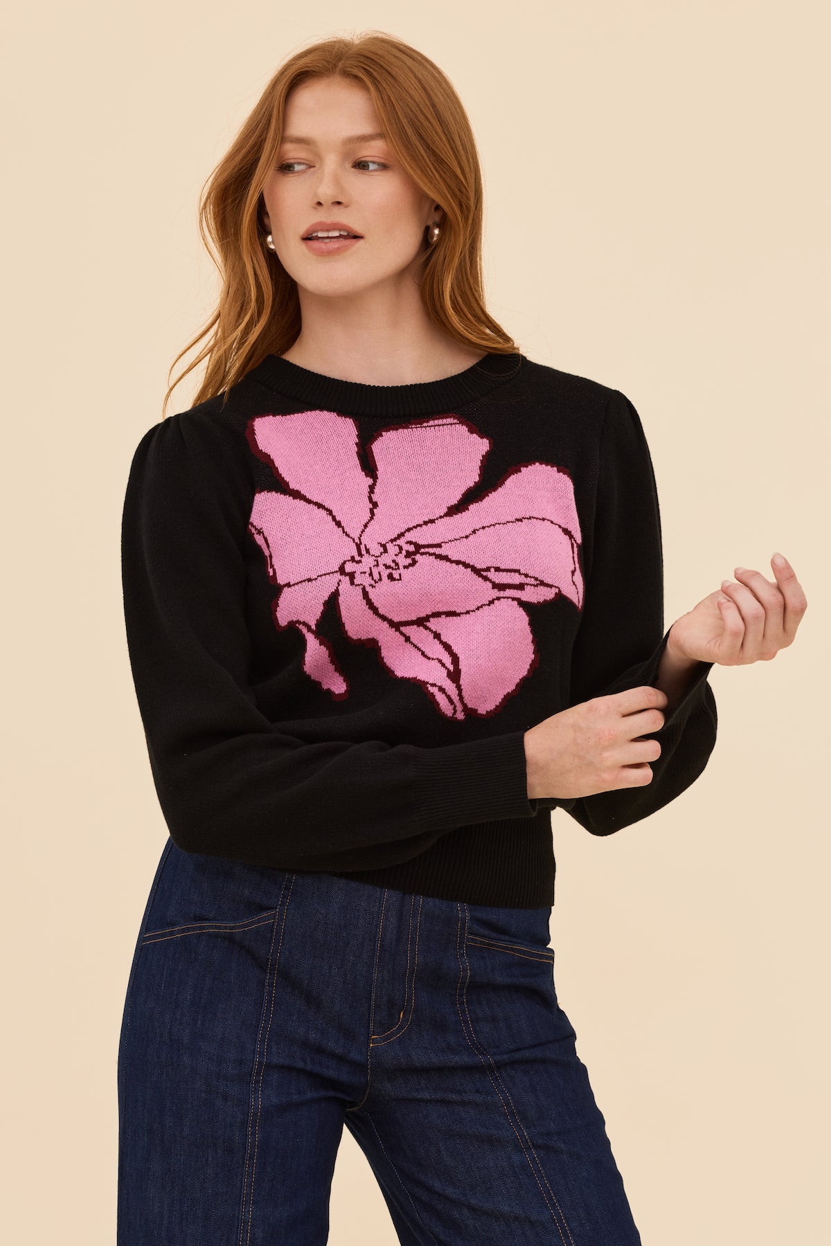 Woman wearing a black jumper with a pink floral design on a beige background