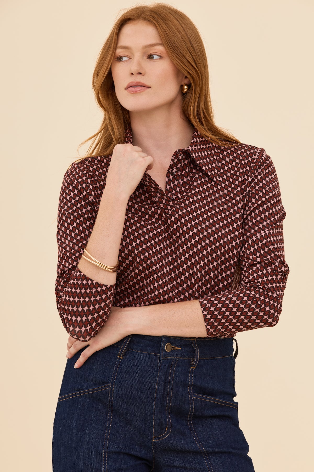 Woman wearing a patterned blouse and jeans on a beige background