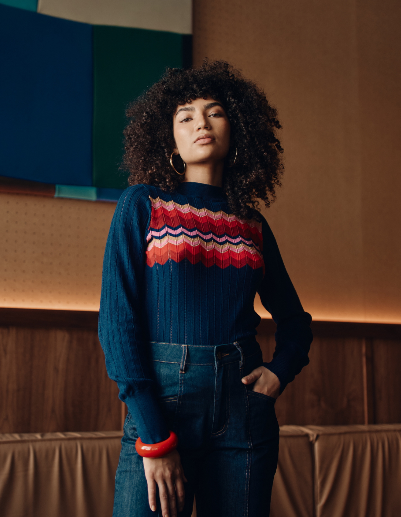 Person wearing a blue sweater with a zig zag pattern in a modern indoor setting