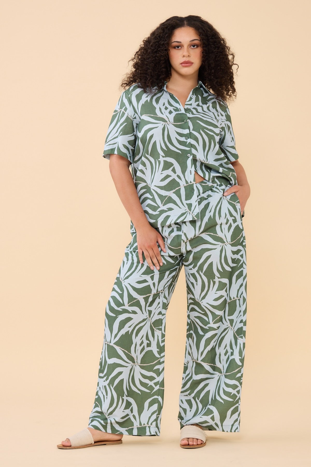 Woman standing wearing the matching Frock Me Out Lets Be Fronds Shirt and Pant set 
