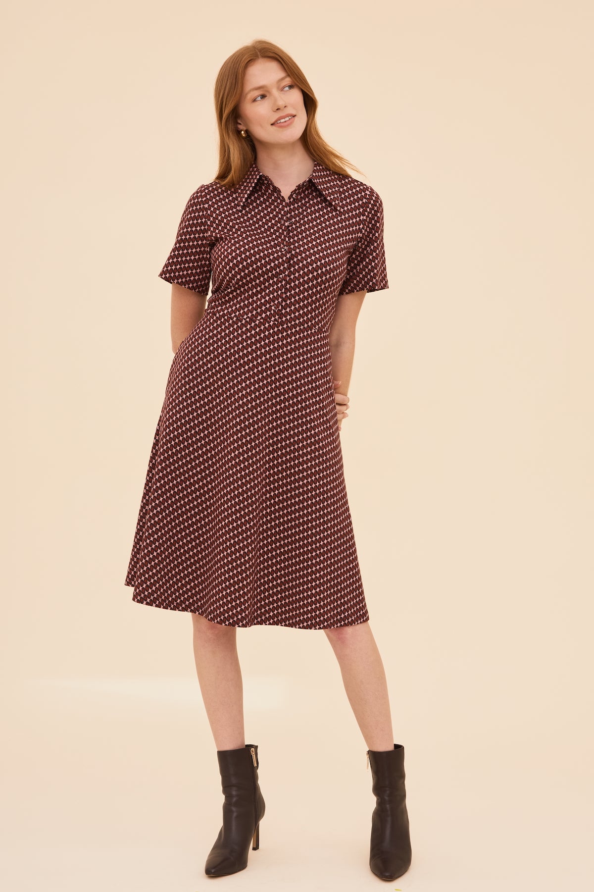 Woman wearing a patterned dress with short sleeves on a beige background