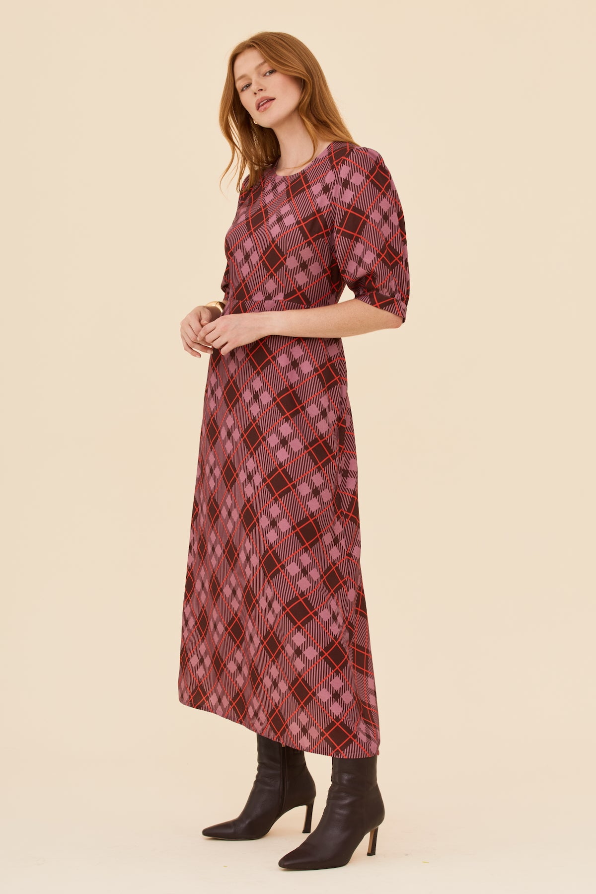 Woman wearing a plaid dress with a beige background